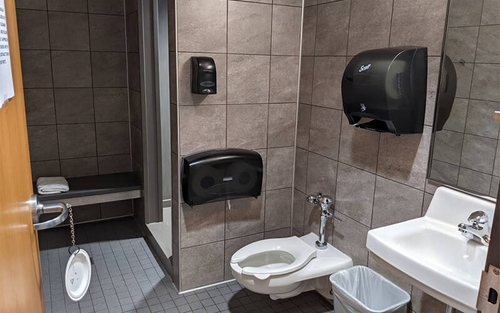 A bathroom stall at Schneider's facility in Dallas contains a shower stall, area to change, toilet, sink and mirror.