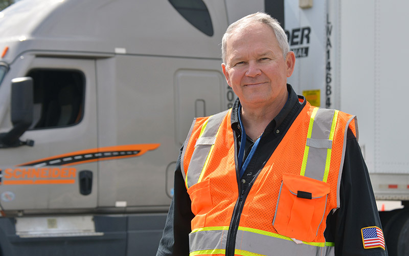 Schneider Training & Development Administrator Brian Johnson standing in front of a Freightliner Cascadia.