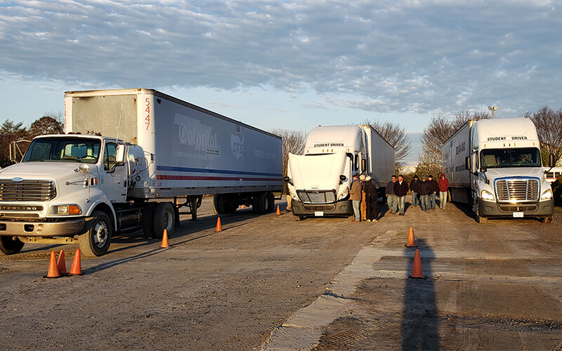 Trucks line up at a driving school ready for students looking to earn their CDL.
