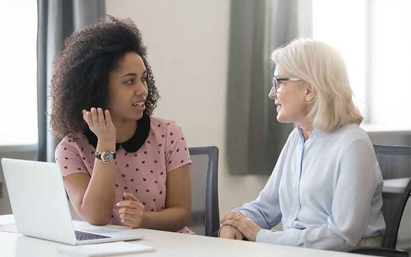 Two women sitting at a table talking.