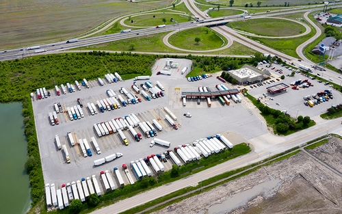 A birds eye view of a truck stop with many semi-trucks parked in the parking lot.