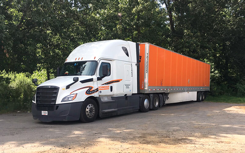 A Schneider truck sits parked in a shaded area between shifts.
