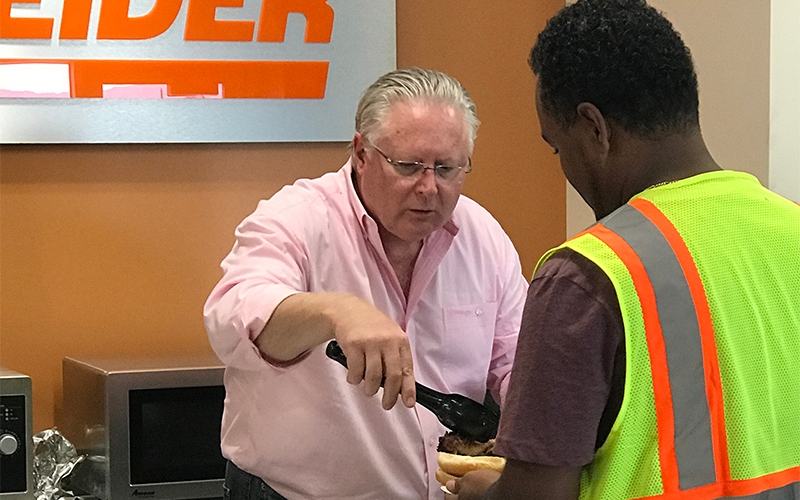 Chris Lofgren serves food to truck drivers at Schneider's Driver Appreciation Week event.