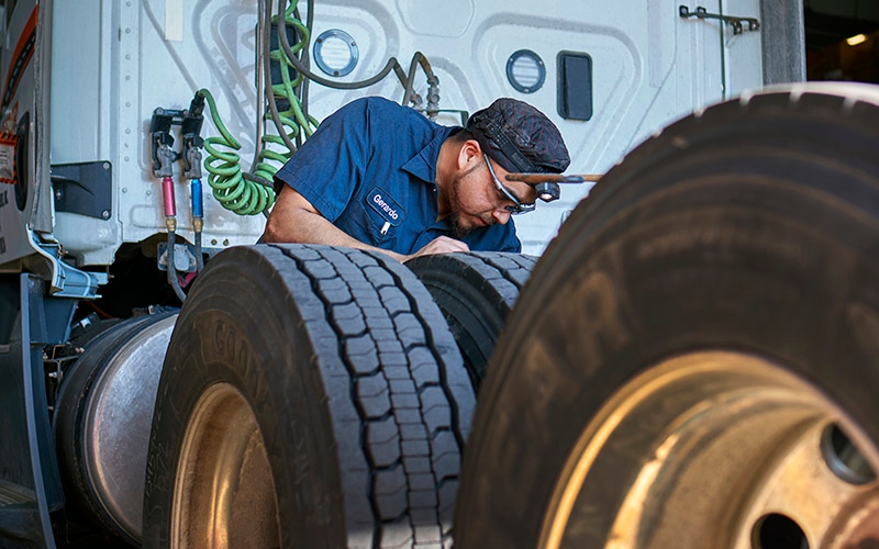 A man repairing the rear tires of a semi-truck.