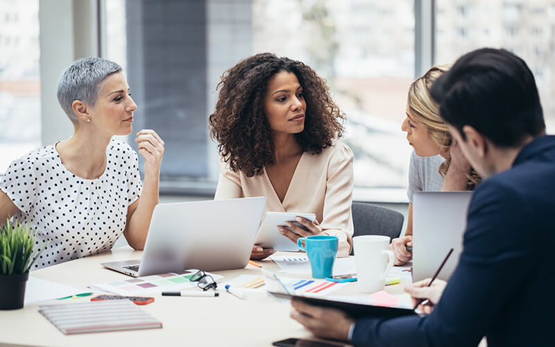 A group of age-diverse associates collaborate in a conference room.