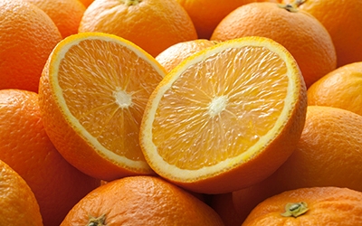 A large pile of oranges topped with one orange that has been sliced in half.