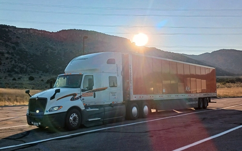 A Schneider truck parked on the side of the street with mountains in the background.