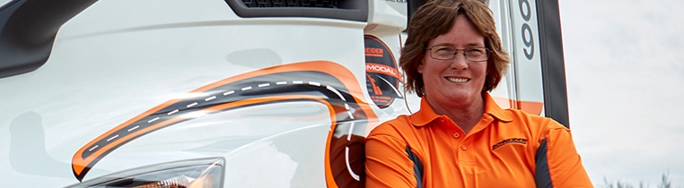 A Schneider truck driver in front of her company truck