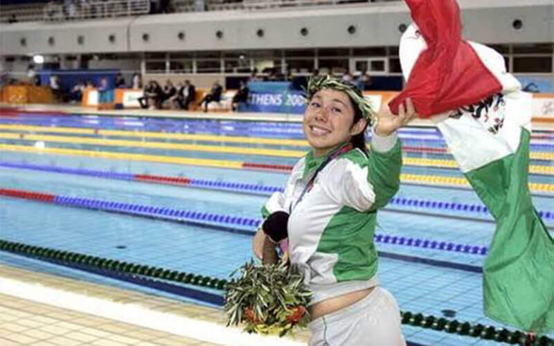 Doramitzi Gonzalez waves while jogging past the pool at the Mexican Paralympics.