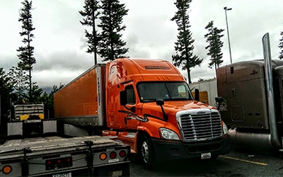 Carl Lindmark's Schneider truck parked near a trailhead where a few towering trees can be seen in the background.