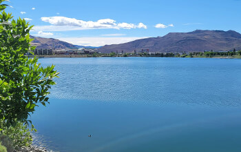 The bright blue waters of the Sparks Marina appear calm and tranquil. The city of Sparks, Nevada and mountains are seen in the distance.