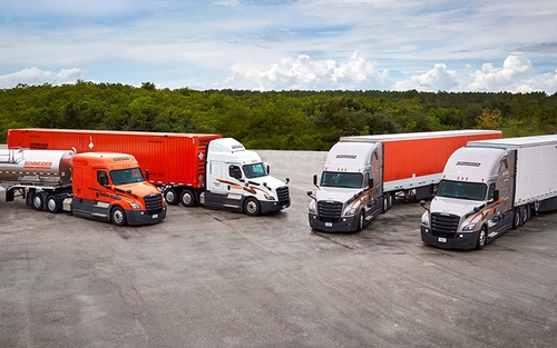 A tanker, intermodal, dry van and dedicated Schneider semi-truck lined up in a parking lot.
