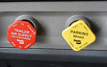 The trailer air supply and parking brake buttons in a semi-truck.