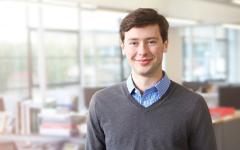 A man standing in an office and smiling. 