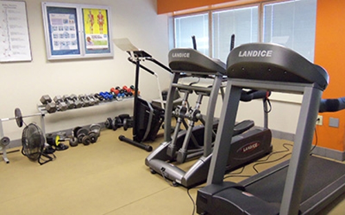 A treadmill, elliptical, stair stepper and weight rack line one corner of a fitness room at a Schneider facility in Indianapolis