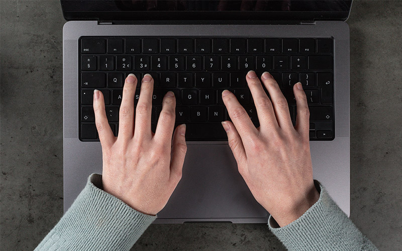 Two hands typing on a black keyboard.