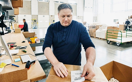 A man putting a label on a package.