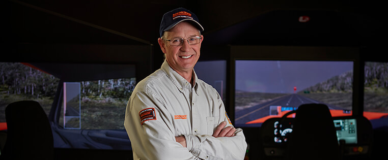 A Schneider training engineer in a truck driving simulation room