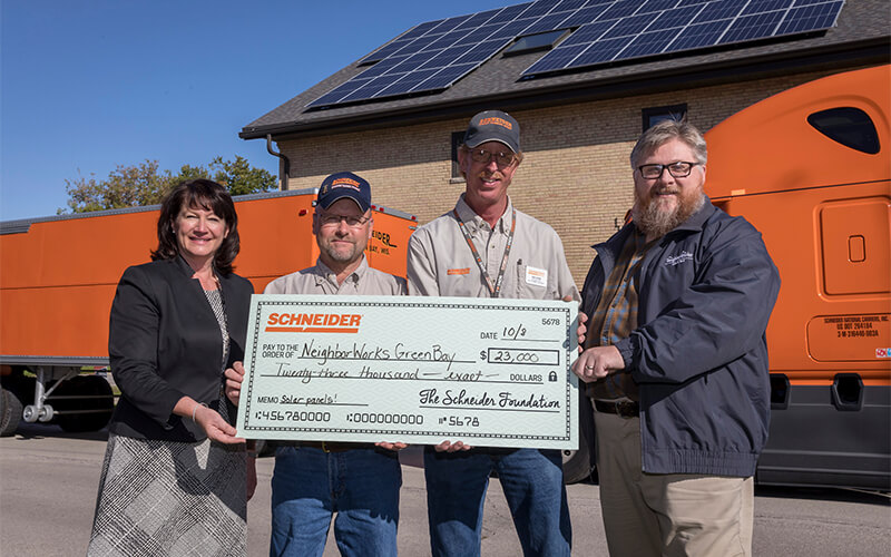 Schneider Foundation presents check to Neighborworks Green Bay for $23,000 to pay for solar panels.