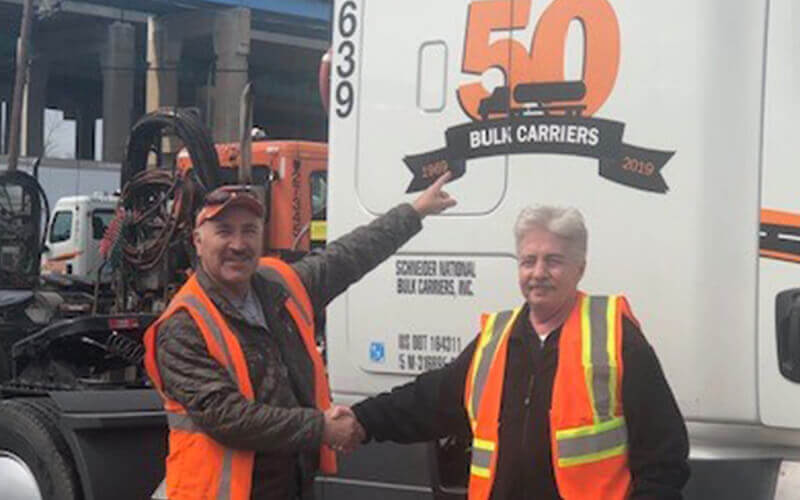 Adrian shakes hands with a leader in front of his 50th Anniversary Bulk Carriers truck decal.