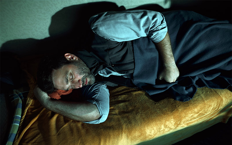 A man sleeping in the sleeper berth of a semi-truck.