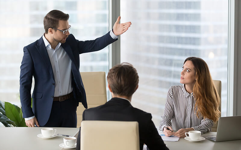 An associate considers a career change while a collogue criticizes her in a meeting.