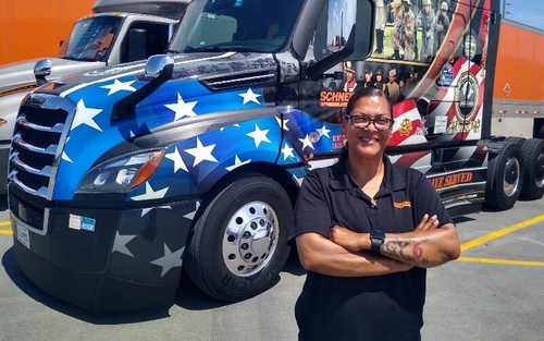 Patrice Cook stands in front of her military-wrapped Ride of Pride semi-truck with her arms crossed.