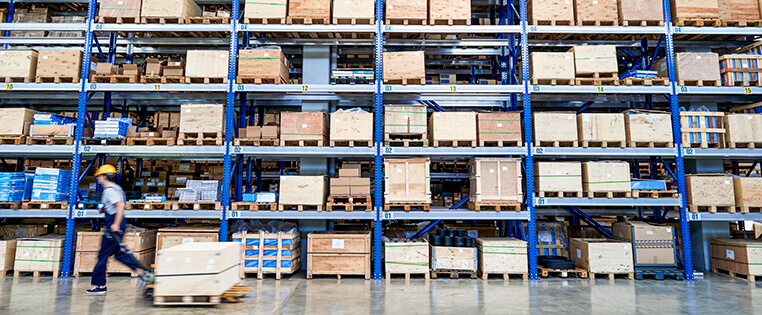 A Schneider associate walks past a large rack of pallets in a company warehouse