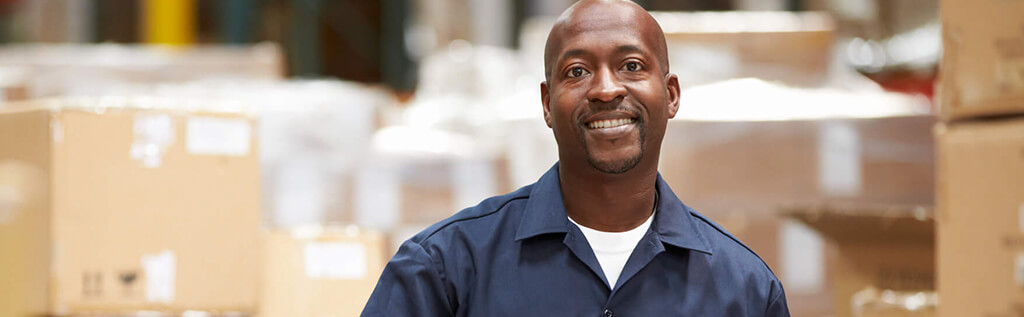 A Schneider warehouse associate poses in front of pallets loaded with packages