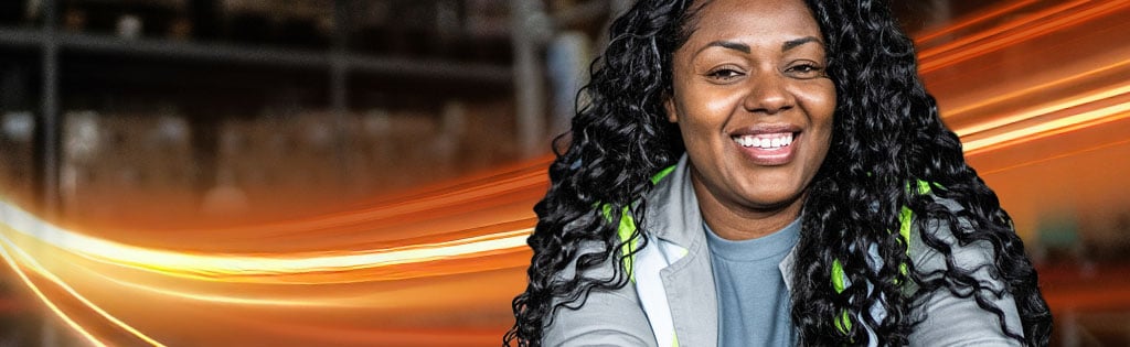 A Schneider warehouse associate poses in front of pallets loaded with packages