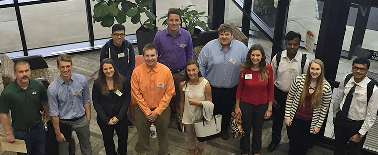A group of seven Schneider interns pose together in the lobby area of the corporate headquarters.