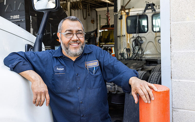 A Schneider diesel technician is standing outside of service bay doors.