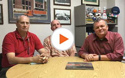 Schneider leaders Stu, Matt and Todd gather around a table in Todd's office.