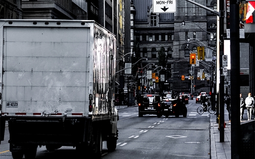 A driver with a Class A CDL drives a box truck down a city street.
