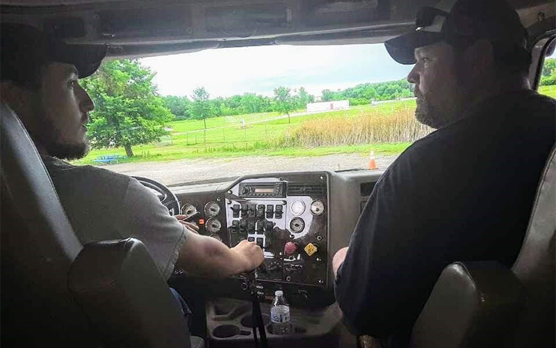 Father teaching son how to drive a semi truck