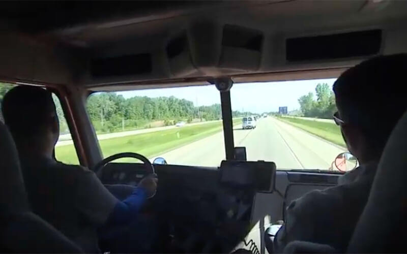 A truck driver gauges a safe following distance while driving down the highway.