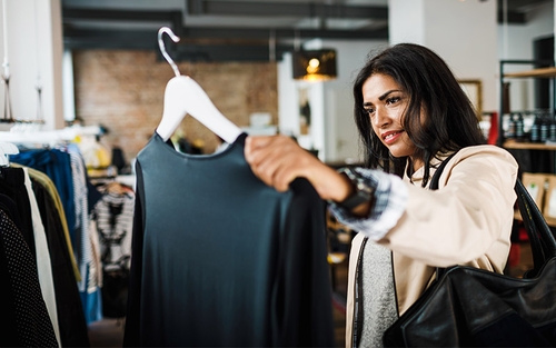 A woman holding up a shirt while shopping at a store.