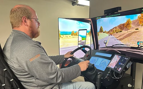A Schneider driver in a grey sweatshirt sitting in one of Schneider's upgraded driver simulators.
