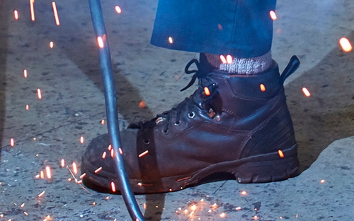 Sparks fly over a diesel technician's leather workboot