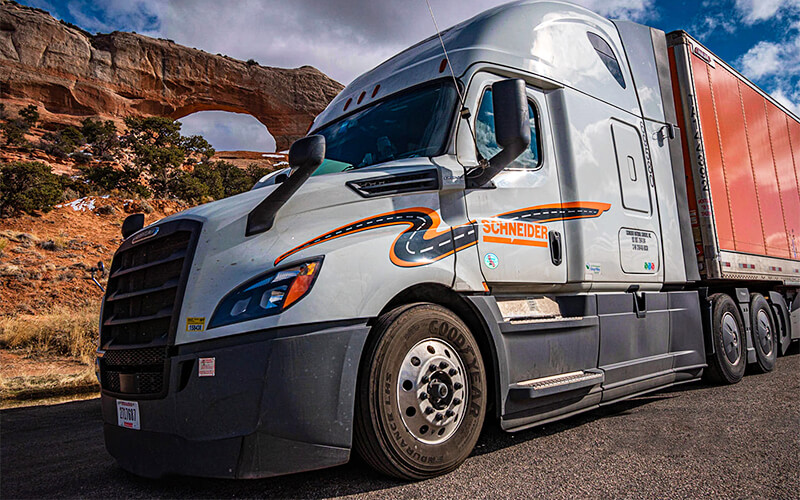 A Schneider truck driving through the desert.