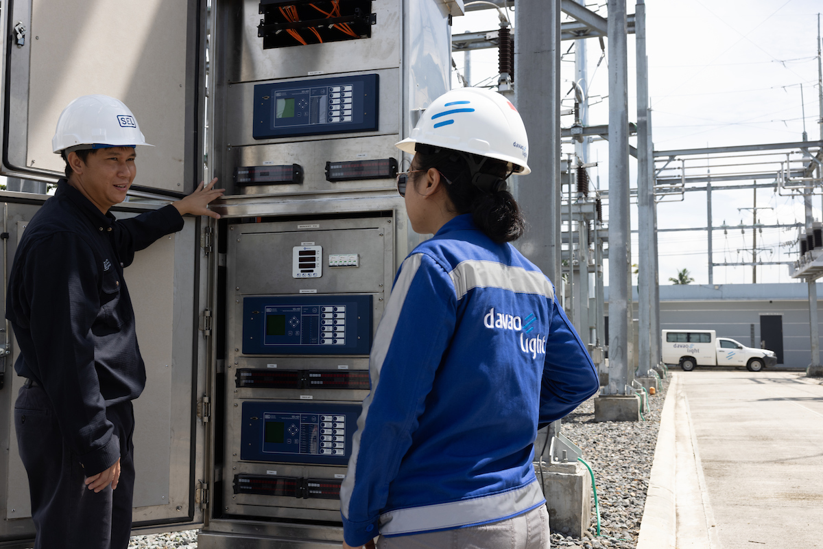 SEL engineer and Davao Light engineer talking in front of an open panel with sel products in place