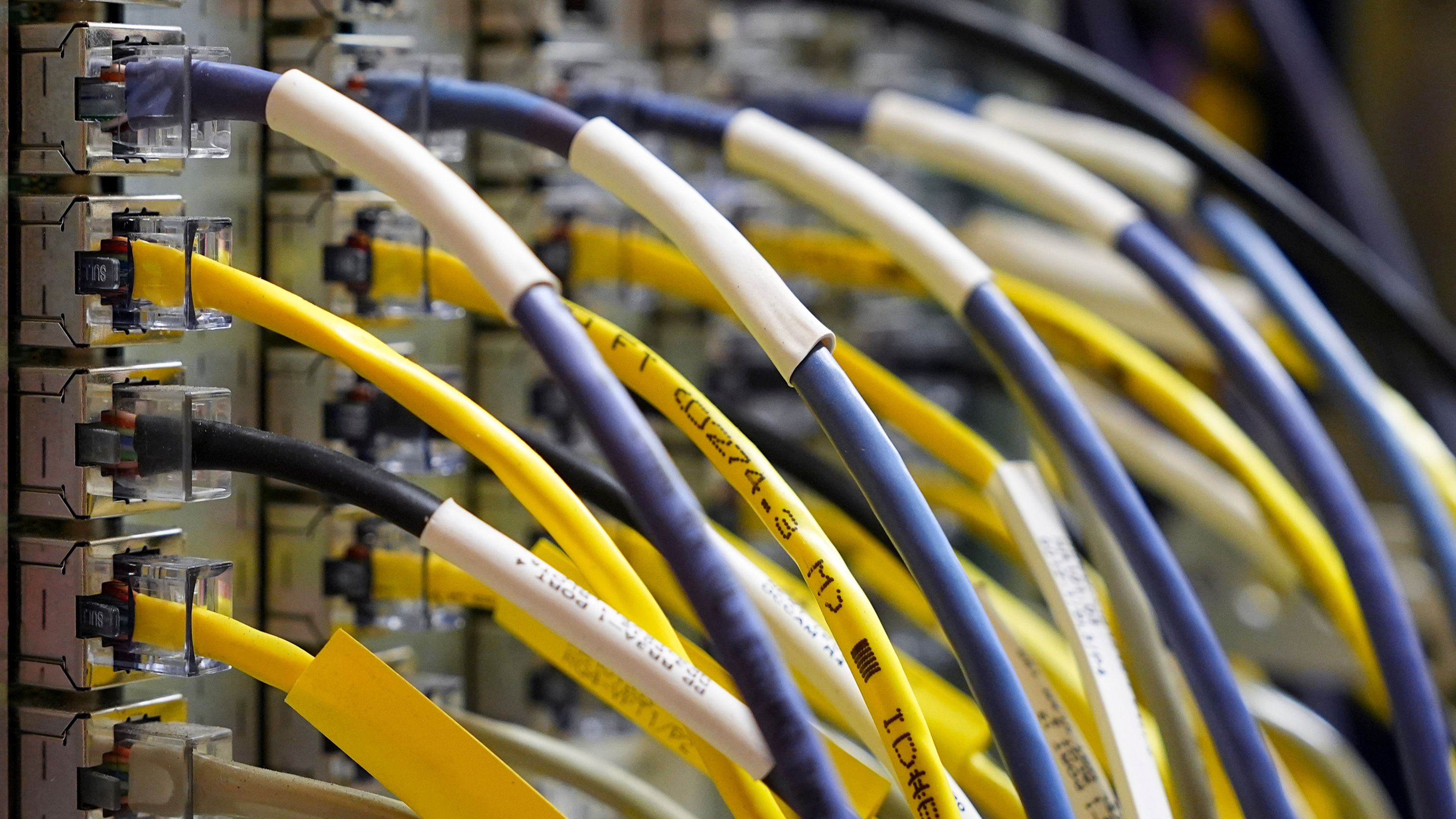 Multiple network cables, primarily yellow and gray, plugged into a server or network switch.