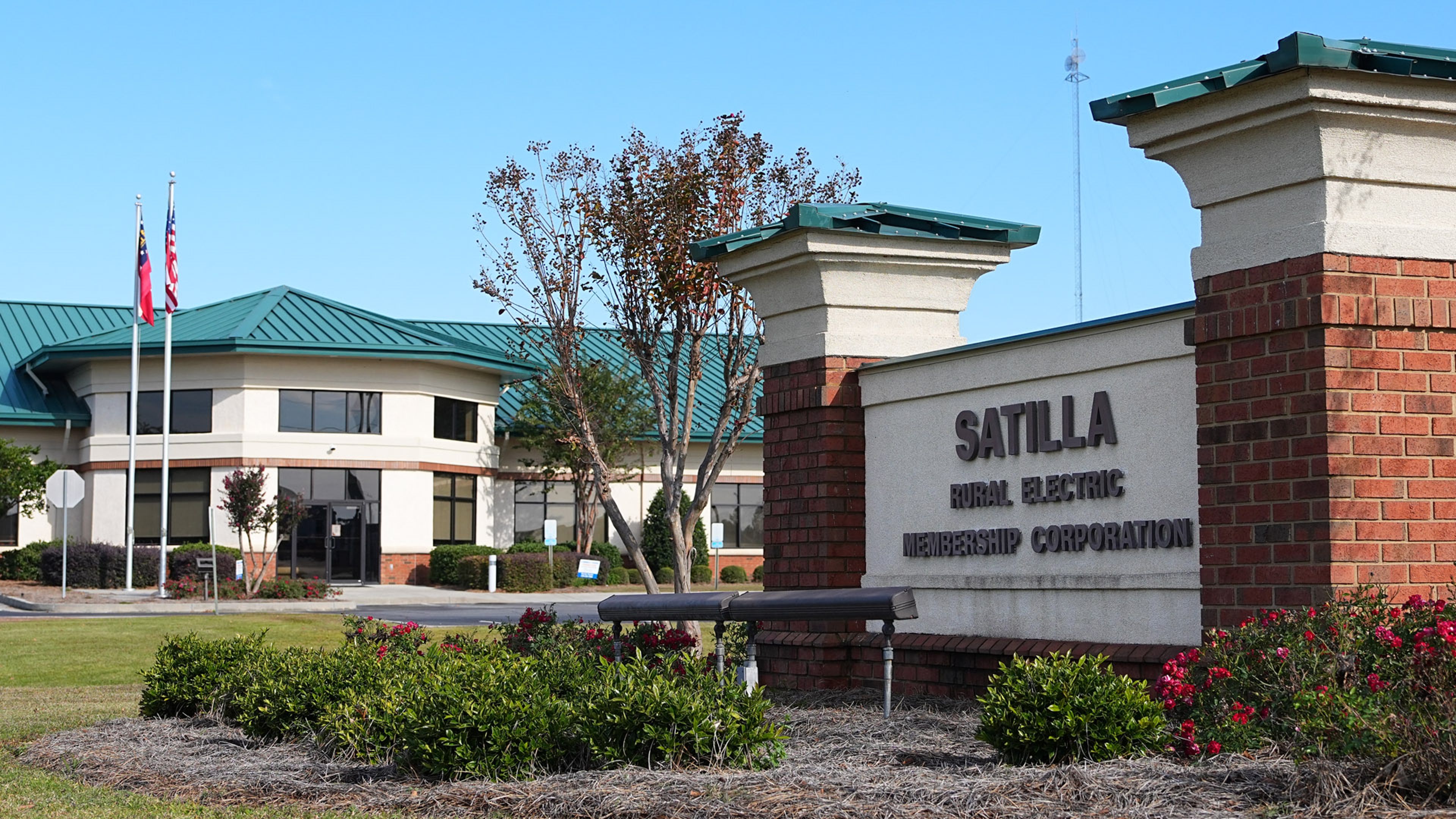 Exterior of the Satilla Rural Electric Membership Corporation office with landscaped grounds and flagpoles.