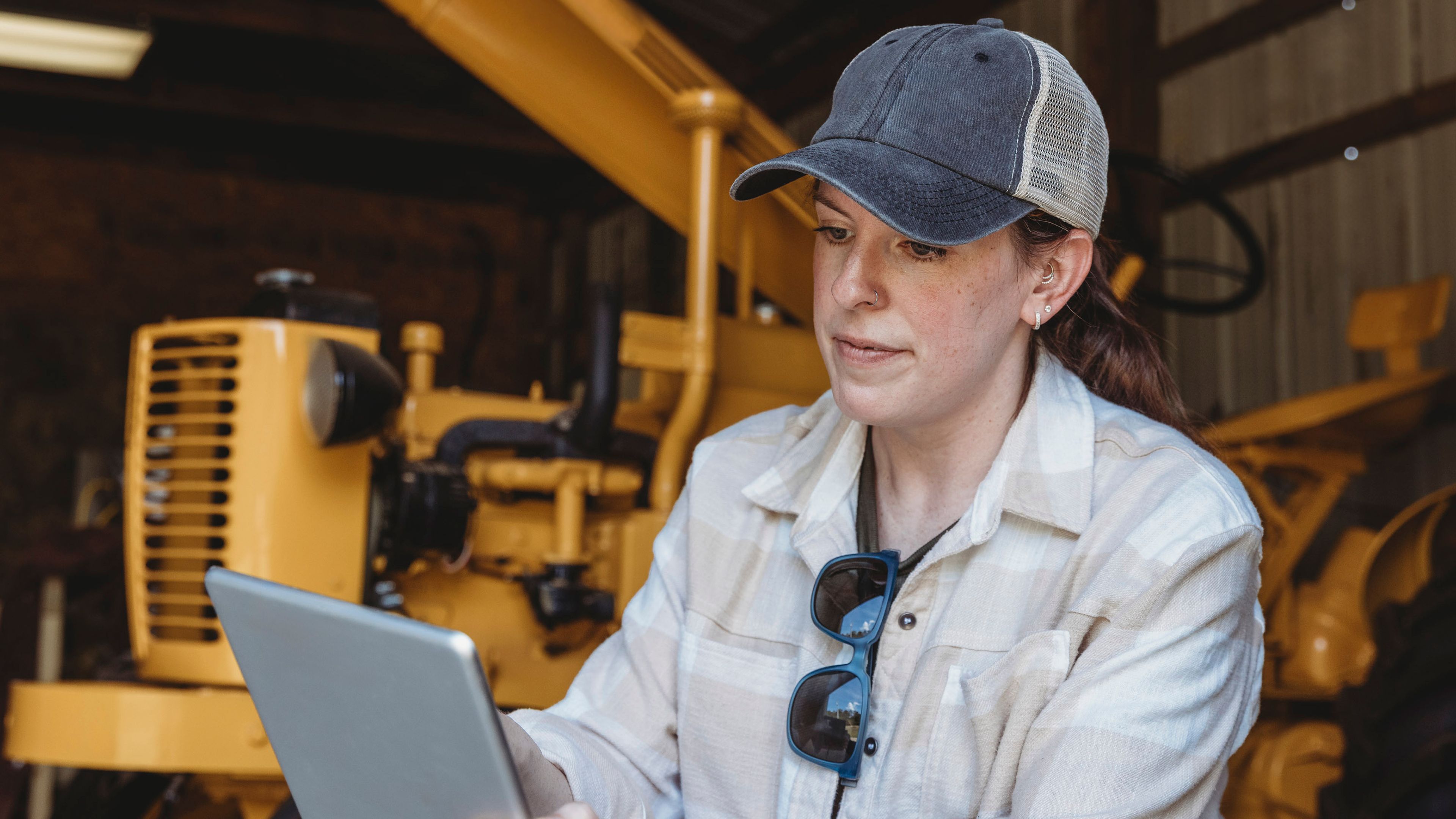 Person working indoors with industrial equipment while using a tablet device to monitor or manage systems