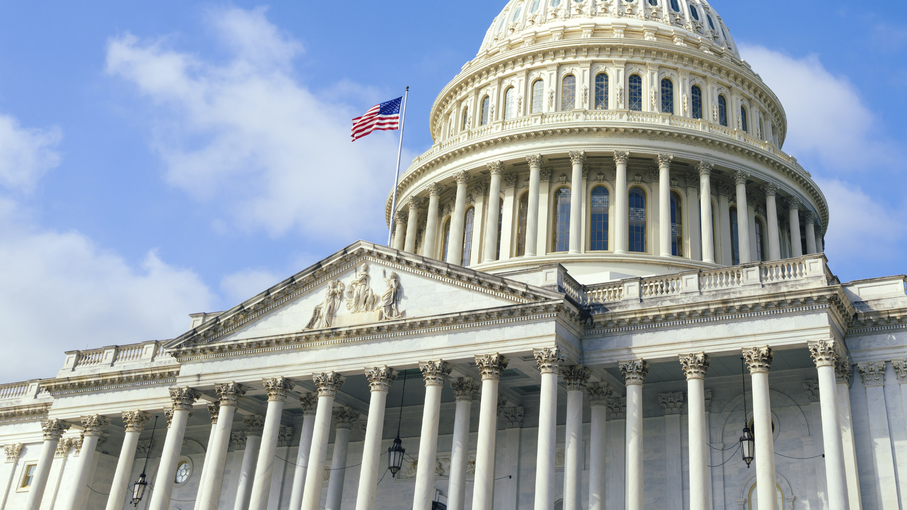 United States Capitol building with American flag over blue sky background, Washington DC 