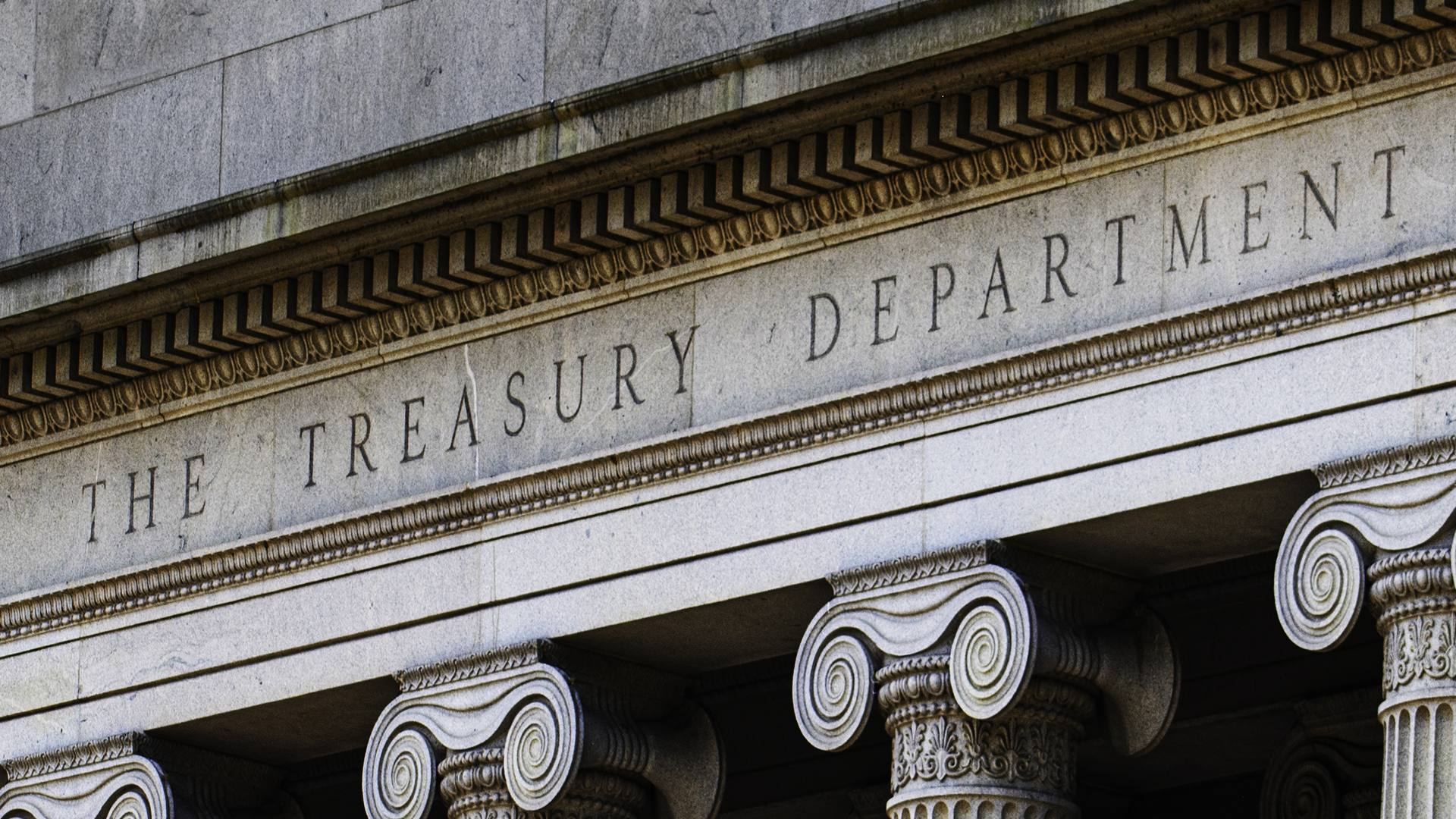Stone facade of the U.S. Treasury Department building featuring classical columns and the engraved words “THE TREASURY DEPARTMENT.”