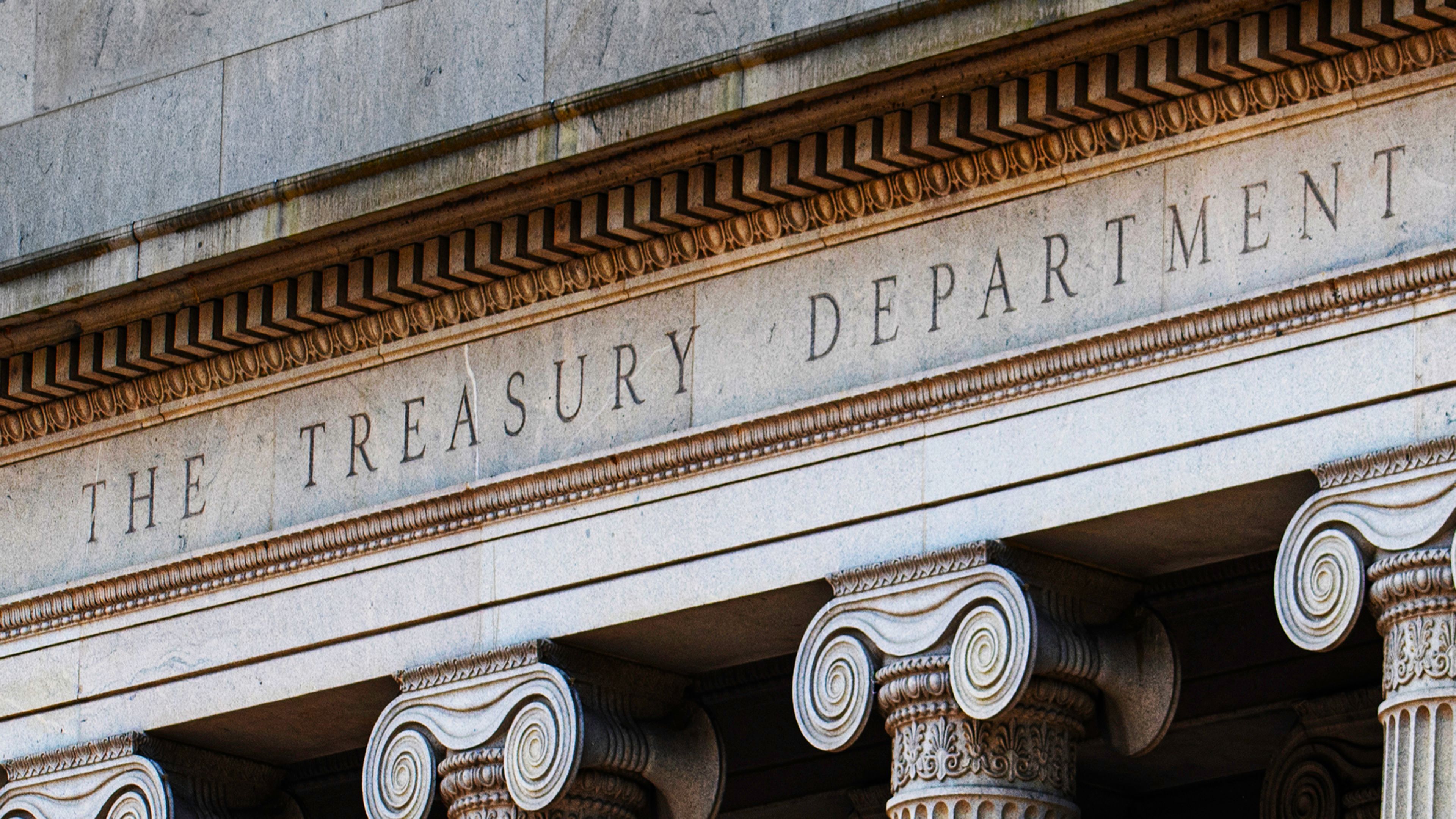 Stone facade of the U.S. Treasury Department building featuring classical columns and the engraved words “THE TREASURY DEPARTMENT.”