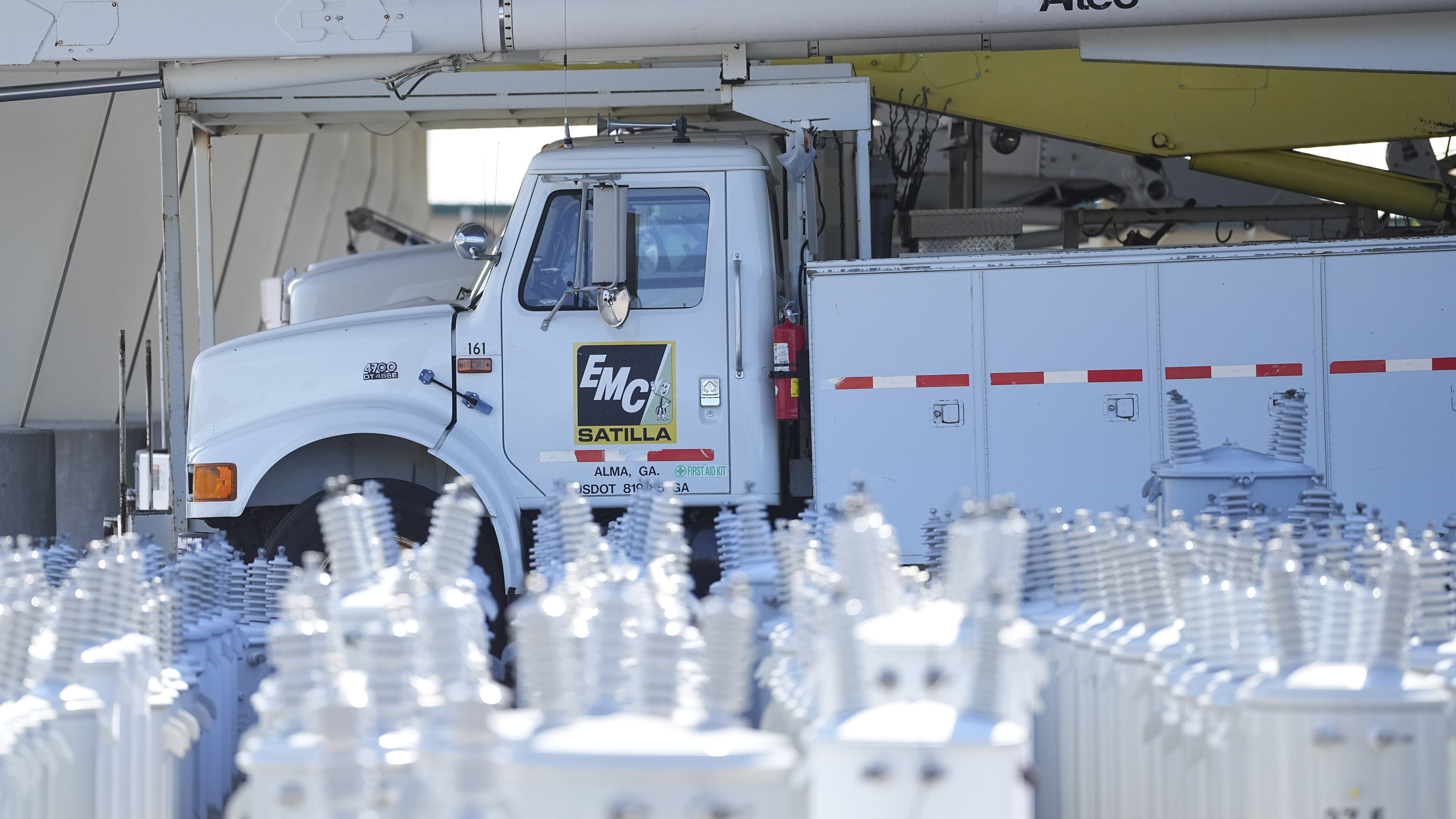 Utility truck parked inside an industrial facility with rows of bottles or containers visible in the foreground and processing equipment in the background