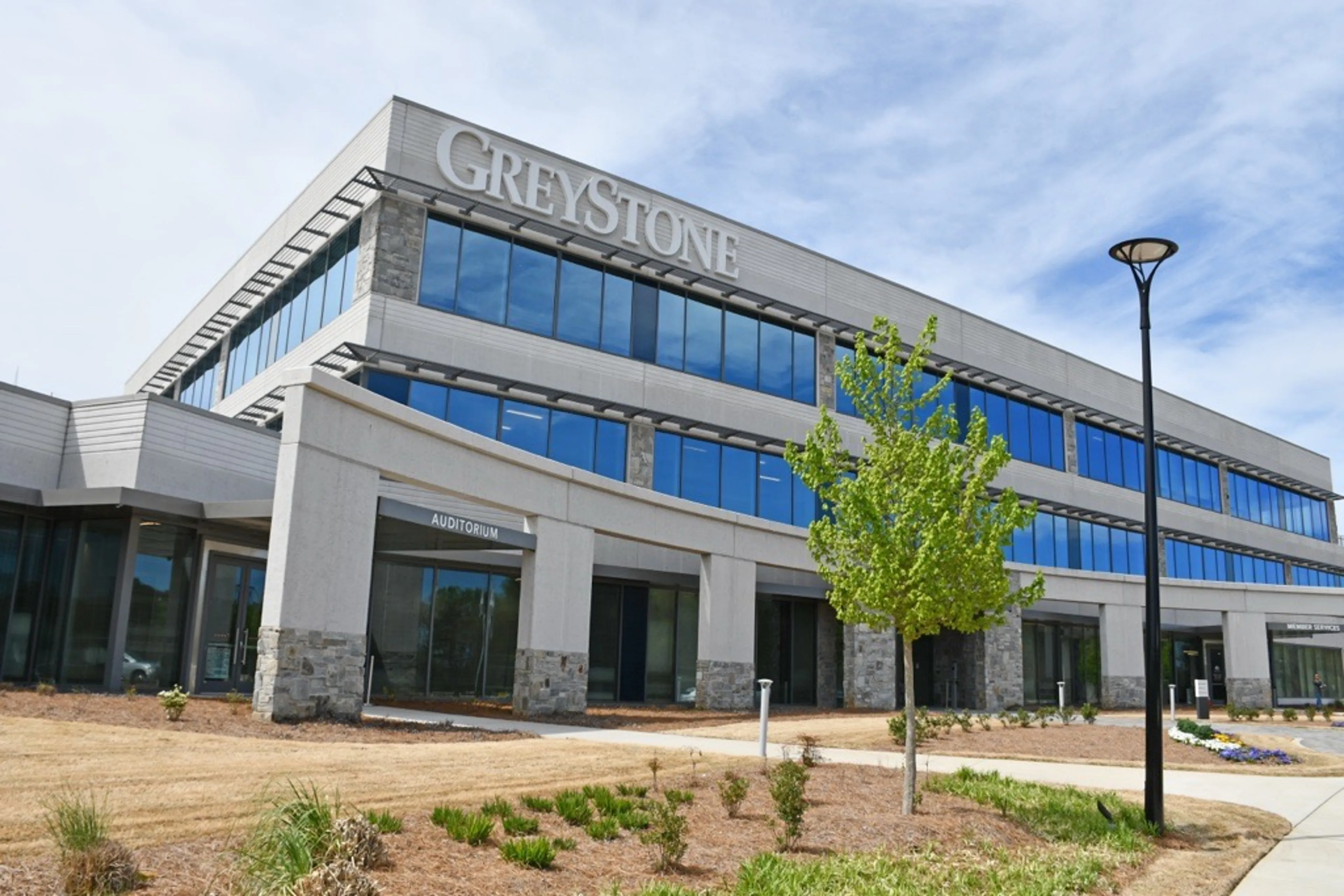 Exterior of GreyStone Power Corporation headquarters, a modern multi‑story office building with glass windows and landscaped grounds.