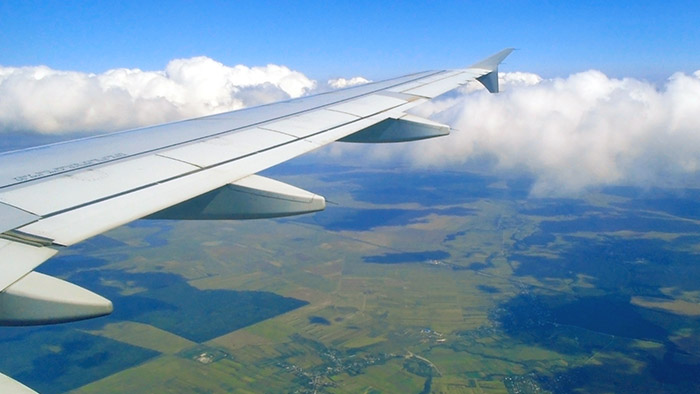Aircraft wing in flight, rural landscape below